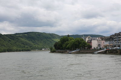 Scenic view of river by buildings against sky