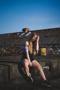 Young woman sitting against clear sky