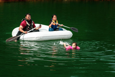 Family wearing life jackets paddling on an inflatable boat in kenyir lake, malaysia.