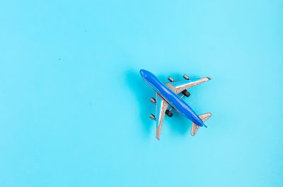 High angle view of airplane flying over swimming pool against blue sky