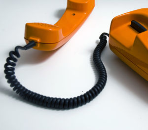 Close-up of orange telephone on table