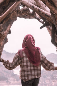 Rear view of woman wearing hijab standing below natural arch