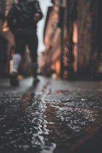 Low section of man walking on wet street