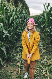 Funny little girl dressed in a yellow raincoat and a hot pink cap spoils 