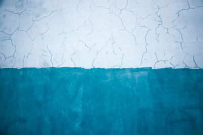 The concrete wall is white and the color of the sea wave. texture with cracked paint. 