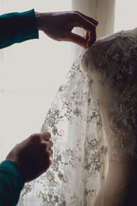 Cropped hands of female fashion designer with wedding dress on mannequin