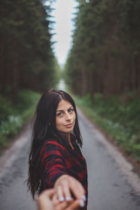 Portrait of young woman standing against trees