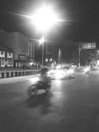 Illuminated street amidst buildings in city at night