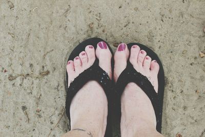 Low section of woman standing on sand