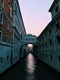 Canal passing through buildings against sky