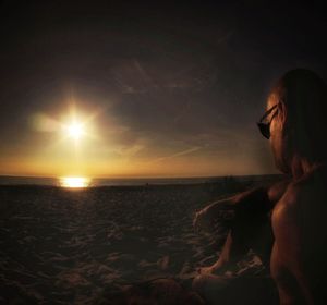 Woman looking at sea against sky during sunset