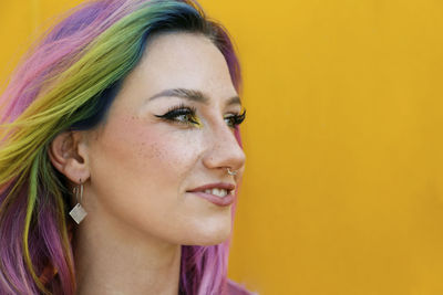 Smiling woman wearing nose ring in front of yellow wall