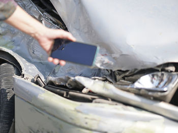 Midsection of man using mobile phone in car