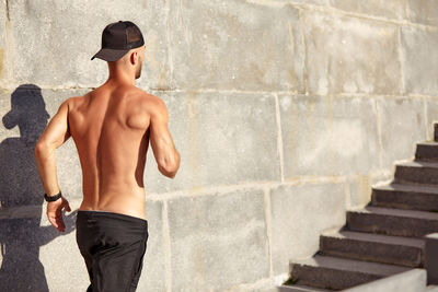 Rear view of shirtless man standing on staircase