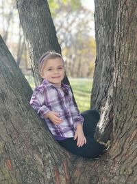 Portrait of cute baby girl on tree trunk