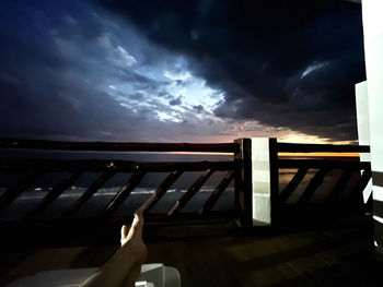 Person relaxing on railing against sky