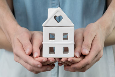 Midsection of man holding small house in building