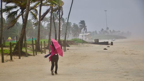 Woman with umbrella walking on wet road during rainy season