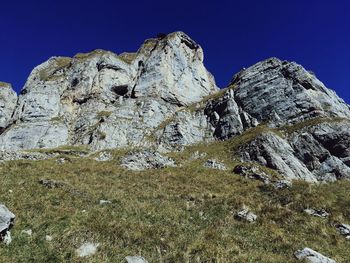 Low angle view of rocky mountains against clear blue sky