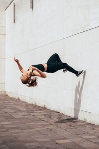 Young parkour and freerunning women doing a backflip from a wall
