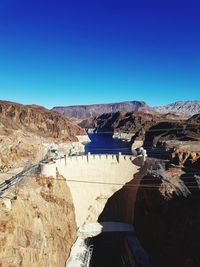 Scenic view of river and mountains against clear blue sky