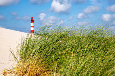 Lighthouse on field against sky