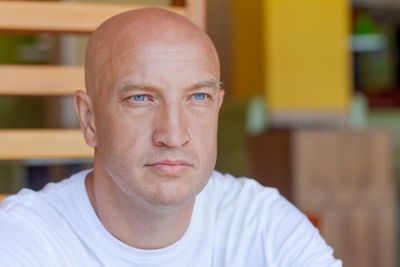 Portrait handsome bald man with blue eyes in a white t-shirt with a pensive