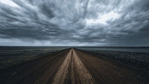 Road amidst field against sky