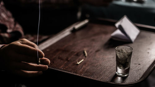 Cropped image of man holding cigarette at table