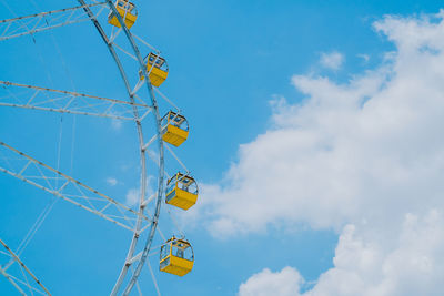 Low angle view of ferris wheel against cloudy sky