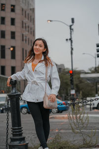 Portrait of smiling young woman standing in city