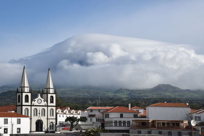 View of madalena city on pico island with the pico mountain covered with clouds