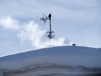 Low angle view of machinery on snow covered landscape against sky