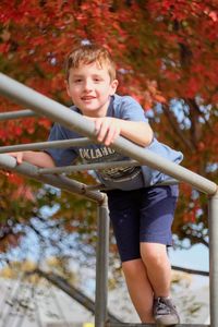 Portrait of boy climbing on railing in playground