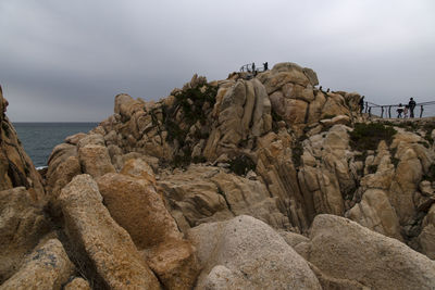 Rock formations on sea shore against sky