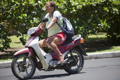 Side view of young woman riding bicycle on road