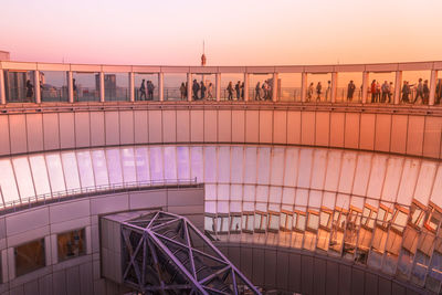 People on bridge against sky at sunset