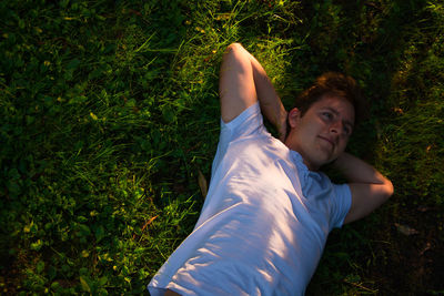 High angle view of young man lying on grassy field