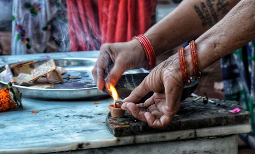 Cropped hands of women igniting diya in temple