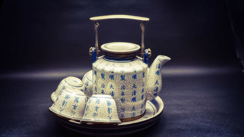 Close-up of teapot and cups in plate on table