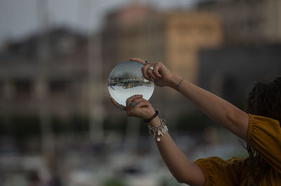Midsection of woman holding crystal ball with reflection