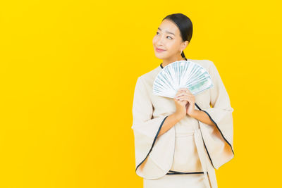 Portrait of smiling woman standing against yellow background