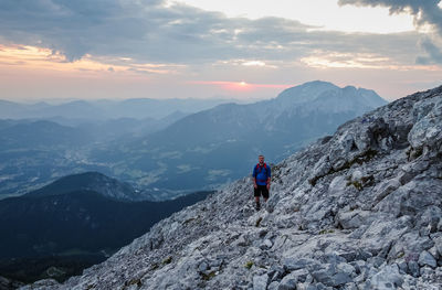 Man on rocks against mountains against sky