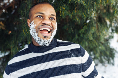 Cheerful funny african man with snow in beard enjoying winter weather
