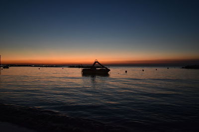 Silhouette boat in sea against clear sky during sunset