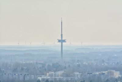 Communications tower in city against sky