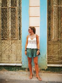 Full length of young woman standing against door