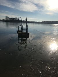 Lifeguard hut on lake against sky during sunset