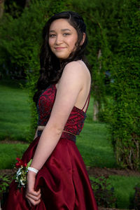 Portrait of smiling young woman in dress standing by plants