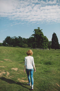 Rear view of mid adult woman walking on grassy field